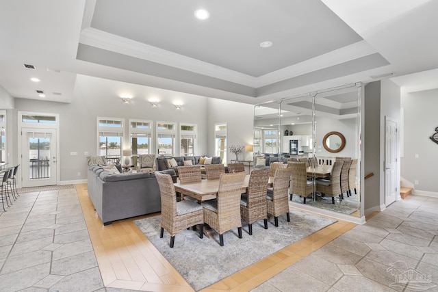 dining room with a raised ceiling, a wealth of natural light, and light hardwood / wood-style floors