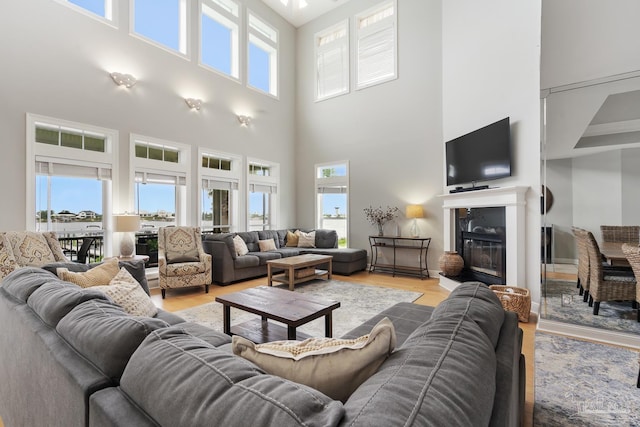 living room with a premium fireplace, light hardwood / wood-style flooring, and a towering ceiling