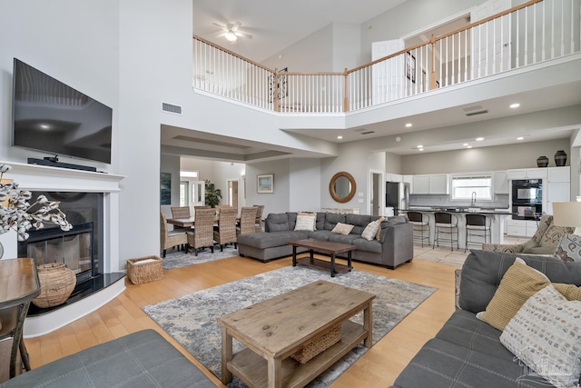 living room featuring sink, a towering ceiling, and light wood-type flooring