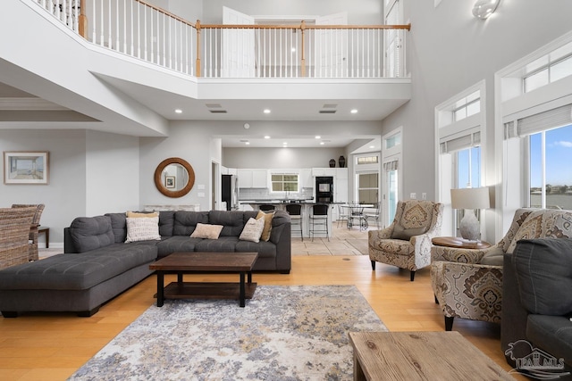 living room featuring a high ceiling, light hardwood / wood-style floors, and crown molding