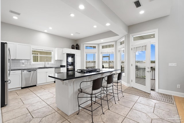 kitchen featuring a wealth of natural light, sink, stainless steel appliances, a kitchen breakfast bar, and a kitchen island