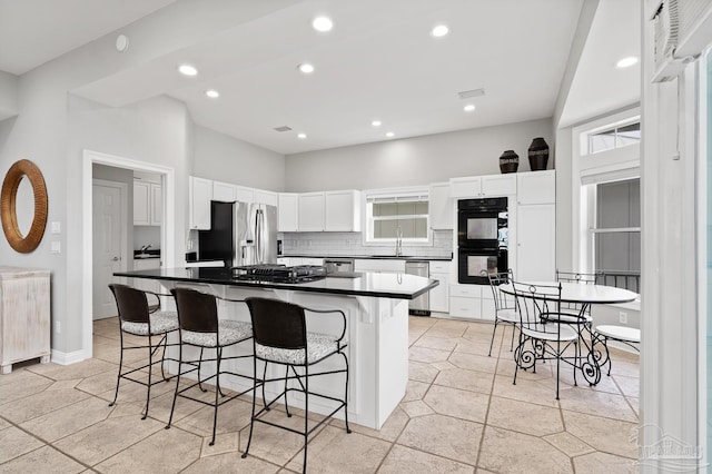 kitchen featuring a center island, stainless steel appliances, a breakfast bar area, decorative backsplash, and white cabinets