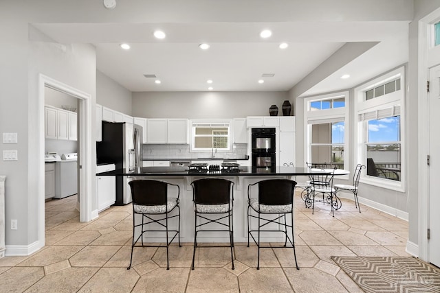 kitchen featuring white cabinets, a healthy amount of sunlight, stainless steel refrigerator, and a breakfast bar area