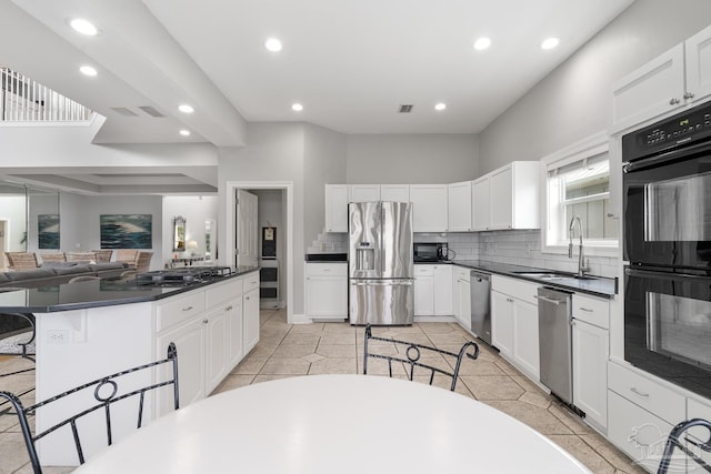 kitchen featuring a kitchen bar, sink, black appliances, a center island, and white cabinetry