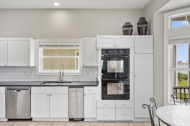 kitchen featuring white cabinets, stainless steel dishwasher, double oven, and sink