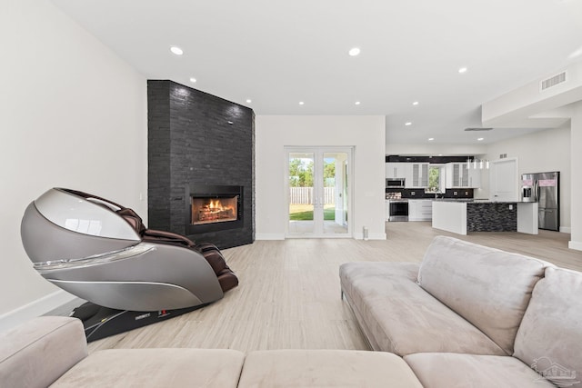 living room featuring a stone fireplace and light wood-type flooring