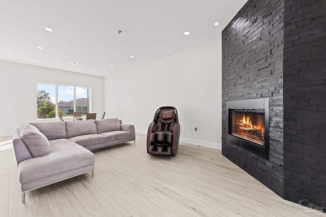 living room with a stone fireplace and light hardwood / wood-style flooring