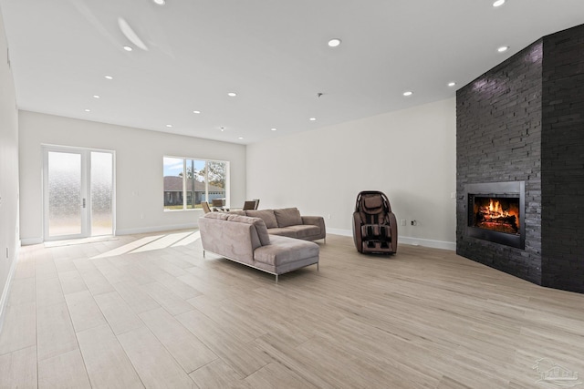 living room featuring french doors, light hardwood / wood-style flooring, and a stone fireplace