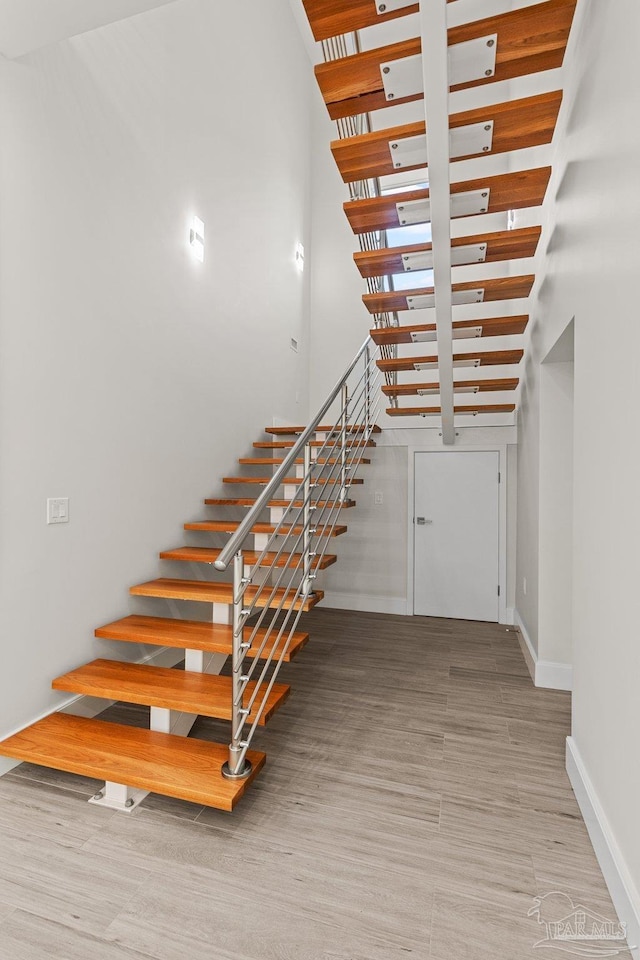 stairs featuring hardwood / wood-style flooring and a high ceiling