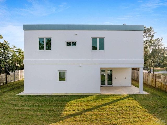 back of property with a lawn, a patio area, and french doors