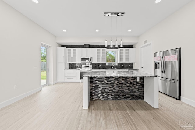 kitchen with a center island, white cabinets, light hardwood / wood-style flooring, appliances with stainless steel finishes, and light stone counters