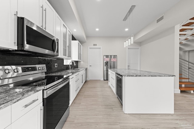 kitchen with stainless steel appliances, sink, light hardwood / wood-style flooring, stone counters, and white cabinetry