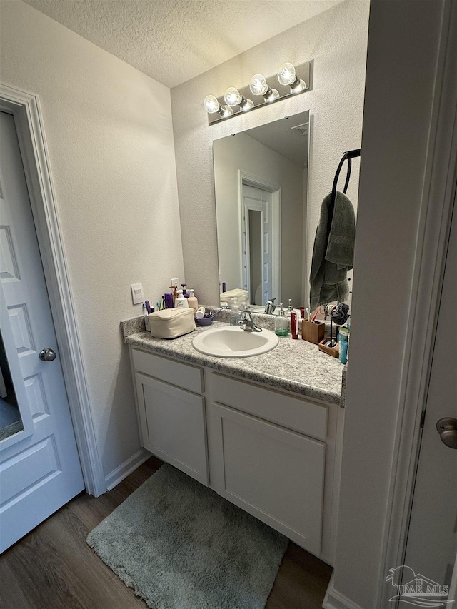 6312 June Bug Dr, Milton, FL 32583 - bathroom featuring a textured ceiling, wood finished floors, and vanity