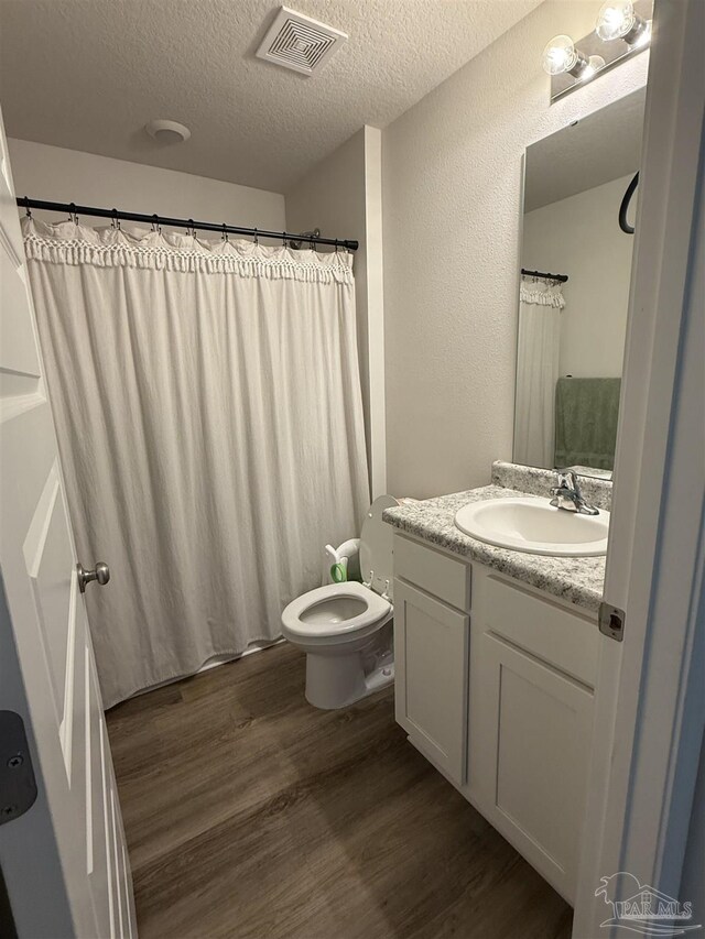 6312 June Bug Dr, Milton, FL 32583 - bathroom featuring visible vents, vanity, wood finished floors, toilet, and a textured ceiling