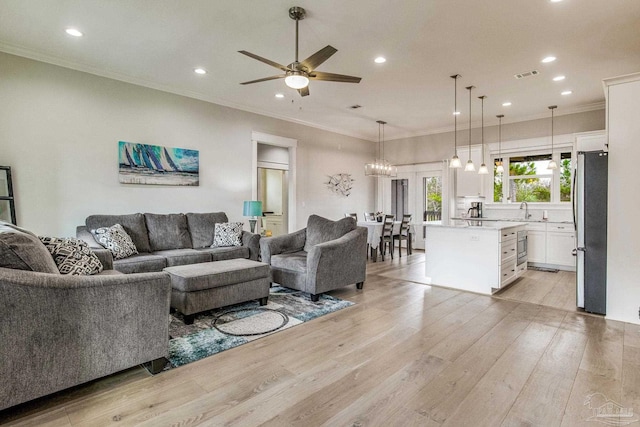 living room featuring sink, ornamental molding, ceiling fan, and light wood-type flooring