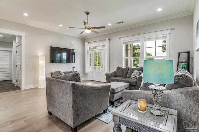 living room featuring ornamental molding, light hardwood / wood-style floors, and ceiling fan