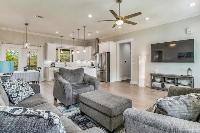 living room featuring sink, crown molding, light hardwood / wood-style flooring, and ceiling fan