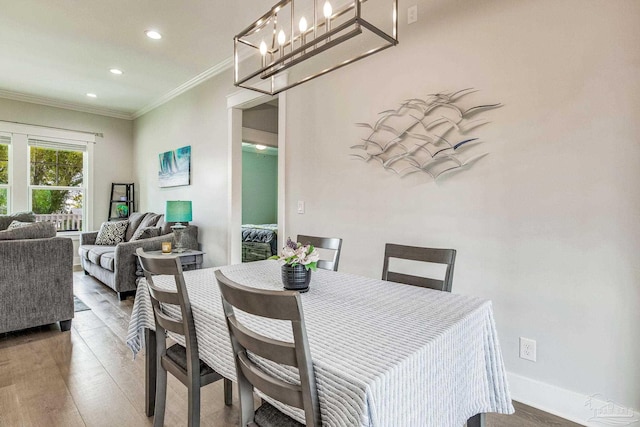 dining space with ornamental molding, hardwood / wood-style floors, and a notable chandelier