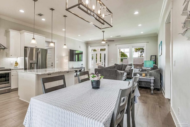 dining space featuring french doors, ceiling fan, ornamental molding, and light wood-type flooring