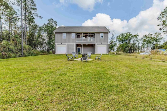 back of house featuring a garage, a balcony, a yard, and a fire pit