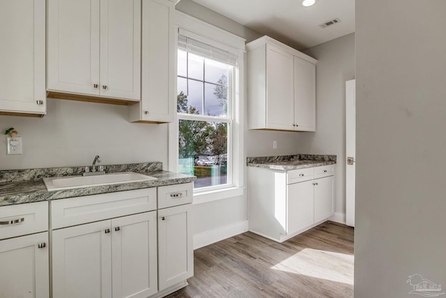 kitchen with sink, light hardwood / wood-style flooring, and white cabinets