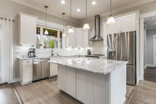 kitchen with white cabinetry, appliances with stainless steel finishes, a center island, and wall chimney exhaust hood