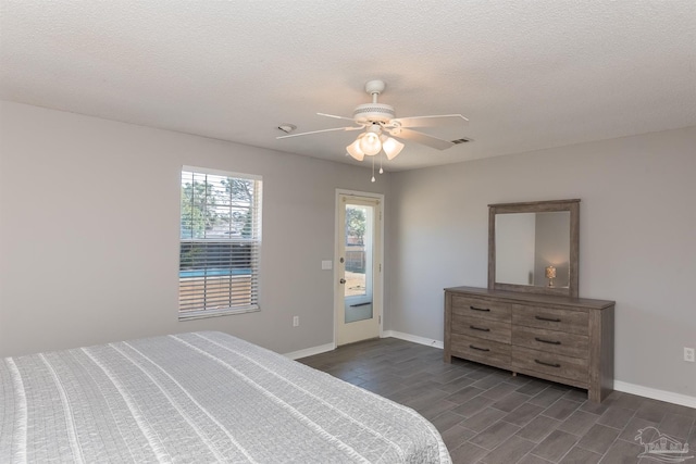 bedroom featuring a ceiling fan, a textured ceiling, baseboards, and dark wood finished floors