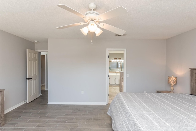 bedroom featuring ceiling fan, a textured ceiling, ensuite bathroom, and baseboards