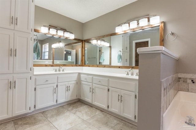 bathroom with tile patterned floors, double vanity, a garden tub, and a sink