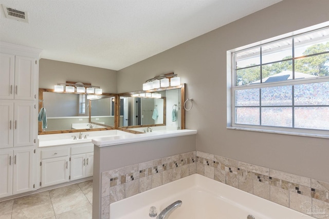 bathroom with a bath, a healthy amount of sunlight, vanity, and visible vents
