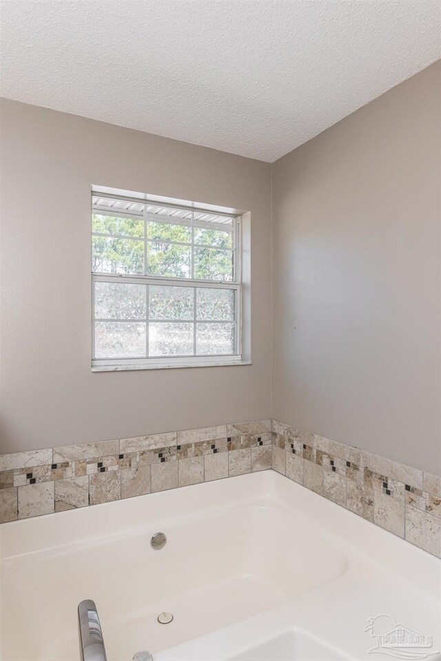 bathroom featuring a textured ceiling, a garden tub, and a healthy amount of sunlight