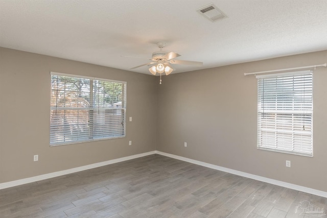 empty room with visible vents, baseboards, a ceiling fan, and wood finished floors