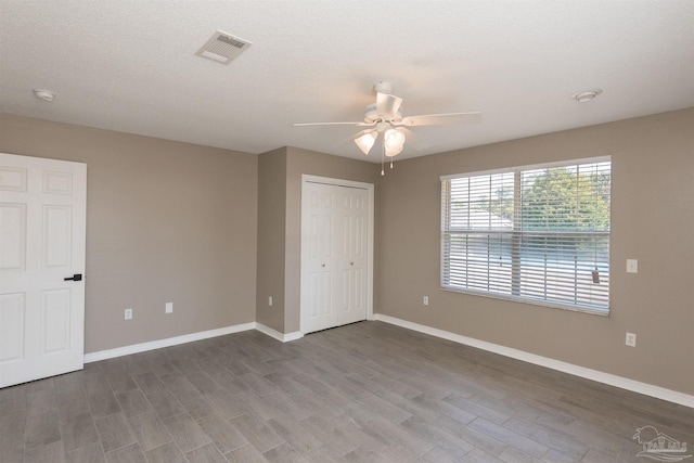 unfurnished bedroom with visible vents, baseboards, a closet, and wood finished floors