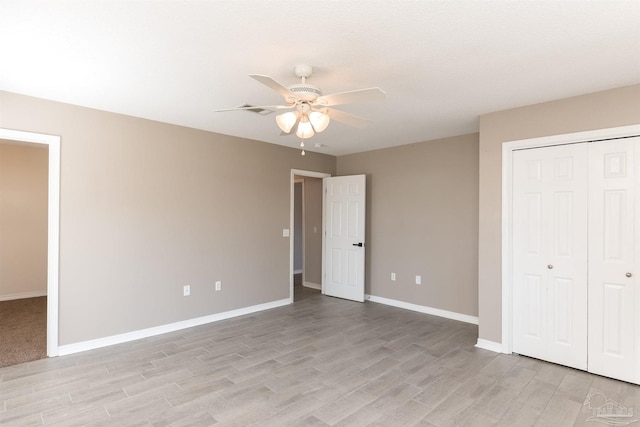 unfurnished bedroom featuring ceiling fan, a closet, light wood finished floors, and baseboards