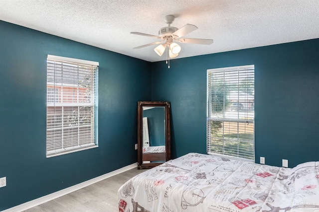bedroom with multiple windows, wood finished floors, and a textured ceiling