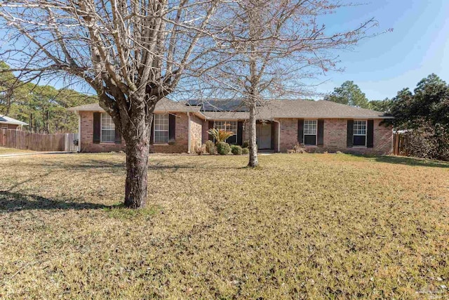 ranch-style house featuring a front yard, fence, solar panels, and brick siding