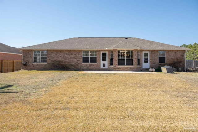 back of property with brick siding, fence, and a lawn