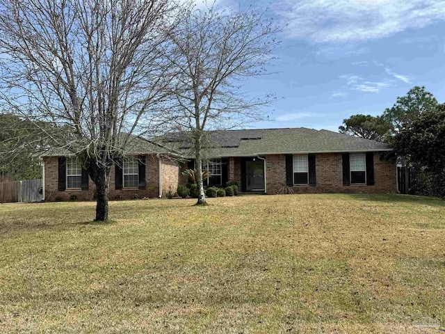 ranch-style home with roof with shingles, brick siding, fence, and a front lawn