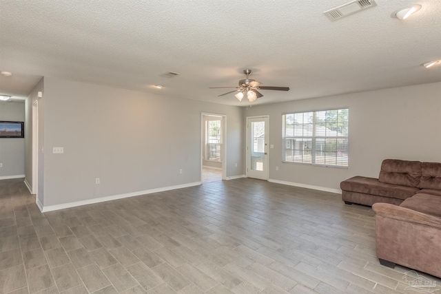 living room with visible vents, ceiling fan, baseboards, and a textured ceiling