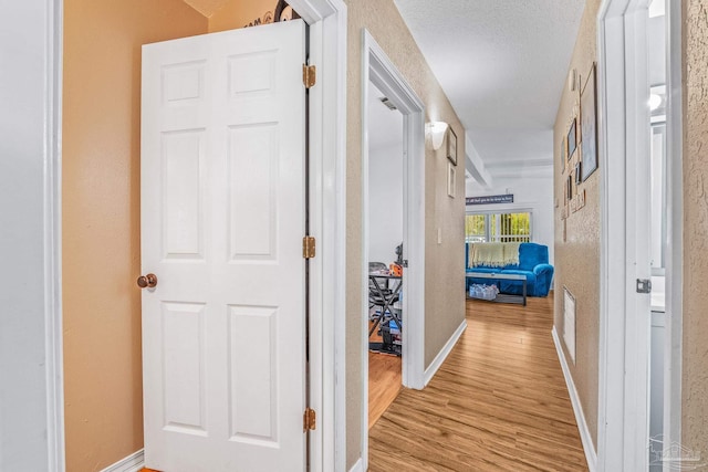 corridor featuring a textured ceiling and light wood-type flooring