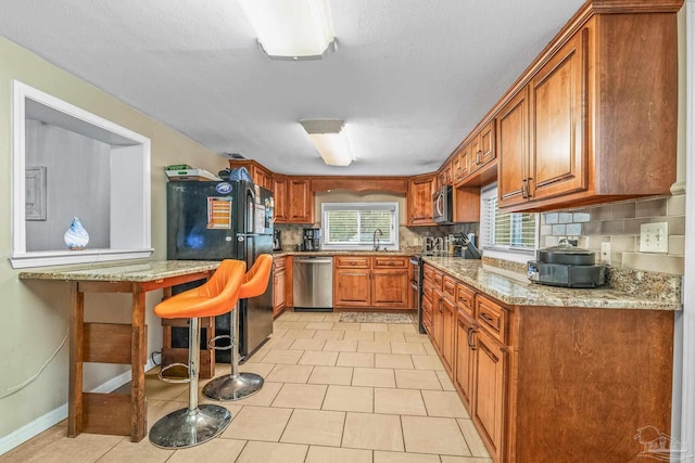 kitchen featuring light tile patterned flooring, sink, backsplash, a kitchen bar, and stainless steel appliances