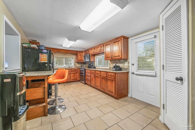 kitchen featuring backsplash, light tile patterned floors, plenty of natural light, and appliances with stainless steel finishes