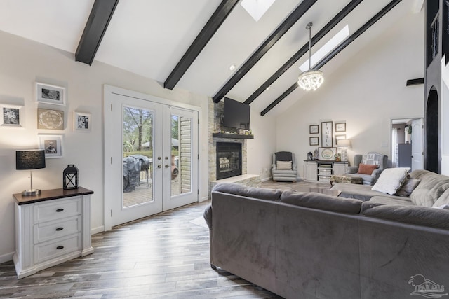 living room with high vaulted ceiling, a fireplace, a skylight, beam ceiling, and french doors