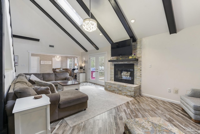 living room featuring light hardwood / wood-style flooring, beam ceiling, high vaulted ceiling, a stone fireplace, and french doors