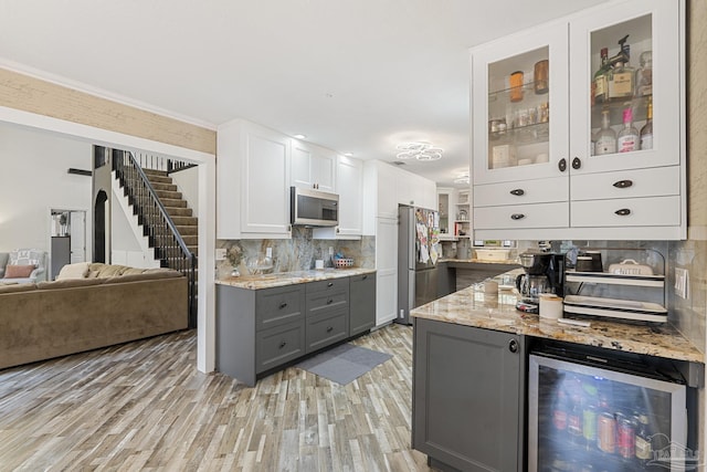 kitchen featuring gray cabinetry, white cabinetry, light stone counters, appliances with stainless steel finishes, and beverage cooler