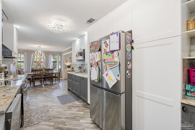 kitchen featuring gray cabinets, appliances with stainless steel finishes, decorative light fixtures, white cabinetry, and light stone countertops