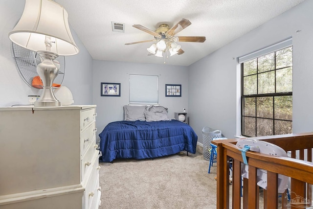 carpeted bedroom with ceiling fan and a textured ceiling