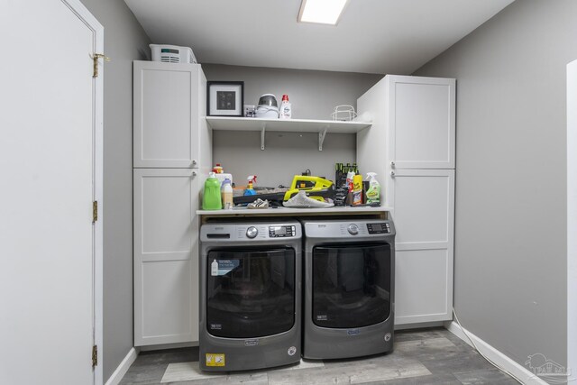 clothes washing area with dark hardwood / wood-style flooring, cabinets, and independent washer and dryer