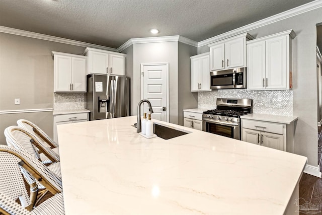 7956 Huntington Creek Ln, Pensacola, FL 32526 - kitchen featuring crown molding, white cabinets, a kitchen island with sink, a sink, and stainless steel appliances