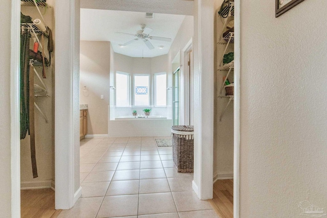 bathroom featuring a textured ceiling, ceiling fan, tile patterned flooring, and tiled bath